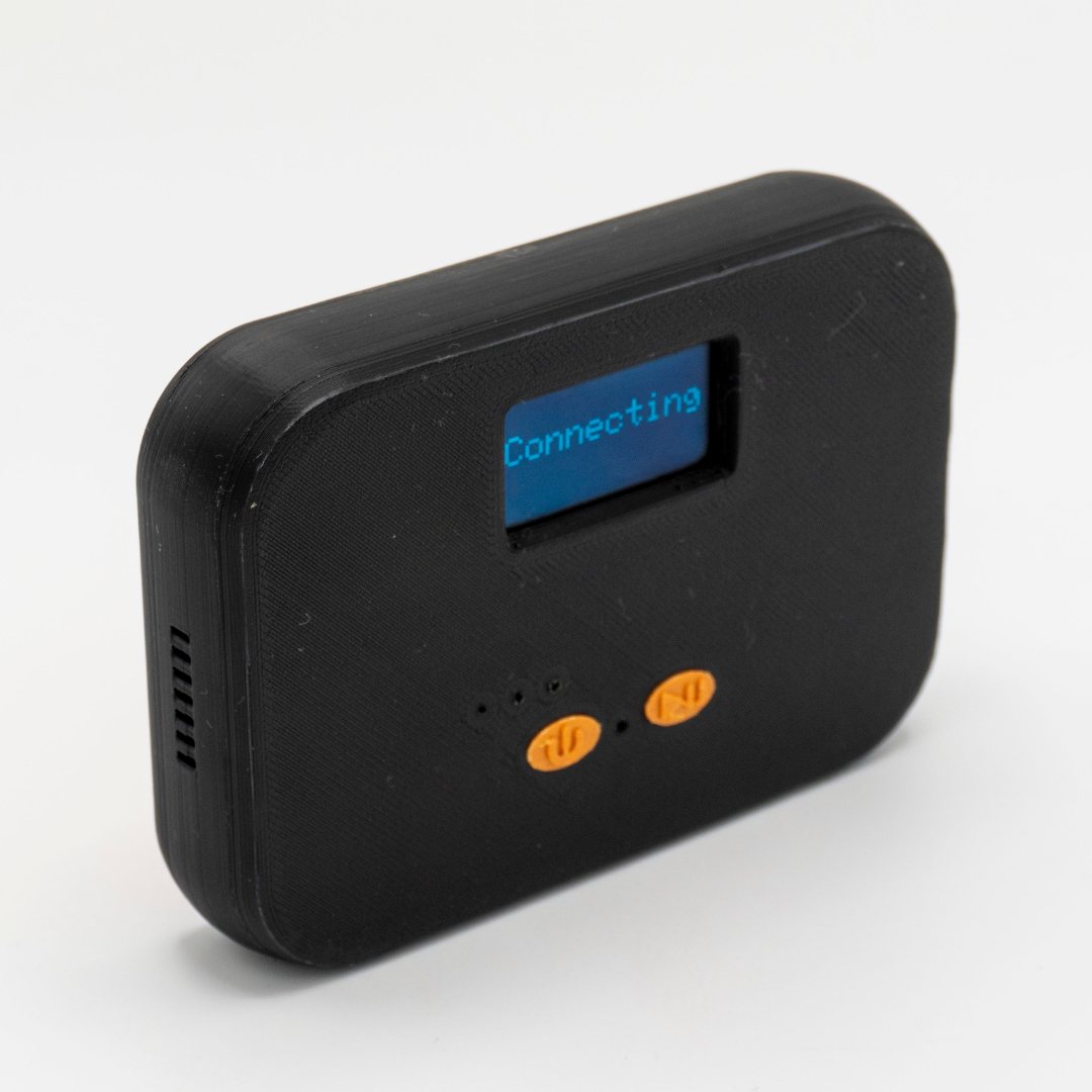 The QuickComm Table Top at a three-quarter angle, status display lit and reading Connecting above the two orange buttons